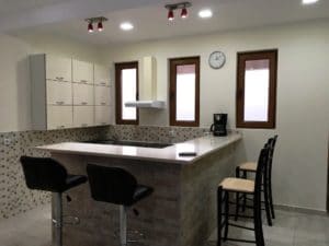 kitchen with bar countertop and bar chairs, three windows