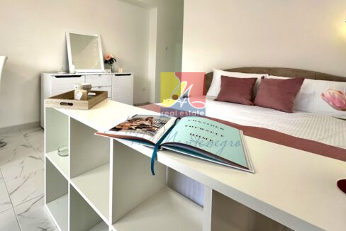 bedroom with a bed, bookshelf in front of the bed with an open book and decorative tray