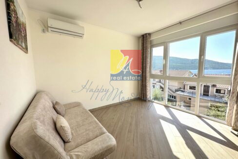sofa in a bright room facing big window with the sea and mountains behind