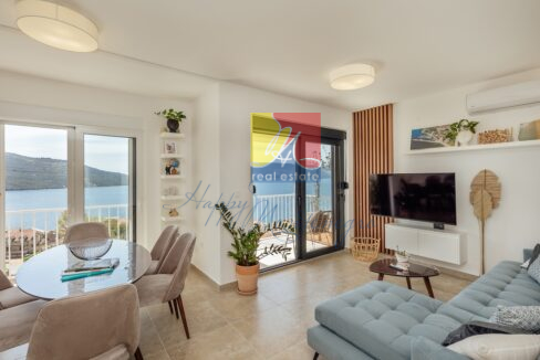 spacious living room with a sofa facing the sea view terrace and a dining area, apartment in Kumbor
