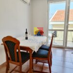 table with chairs and wine bottle and a window with a sea view