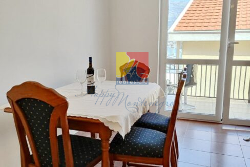 table with chairs and wine bottle and a window with a sea view